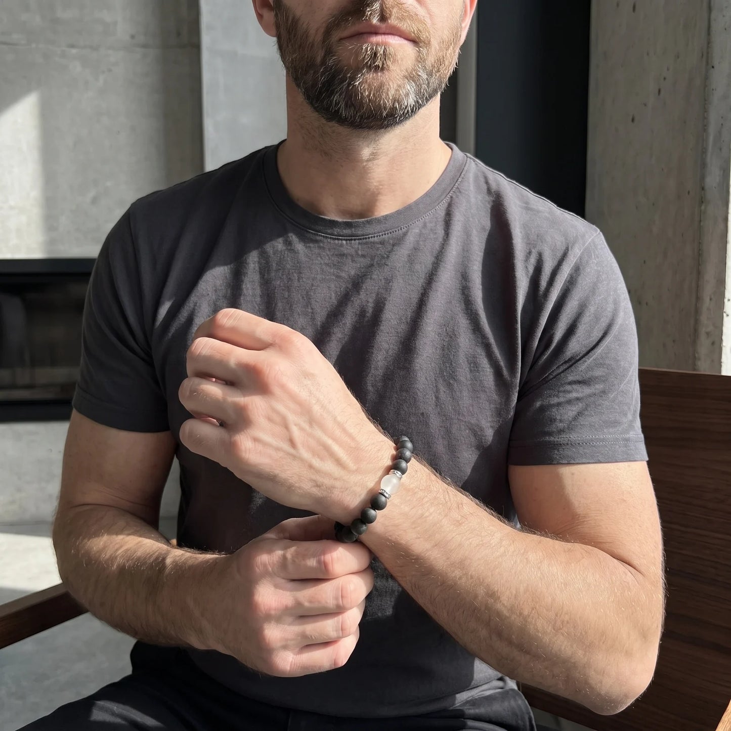 STILL POINT wearable incense bracelet worn with a gray shirt in a quiet modern interior.