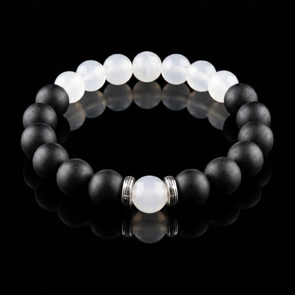 SKIN BREATH Still Mind wearable incense bracelet with black and white beads on a black reflective surface.