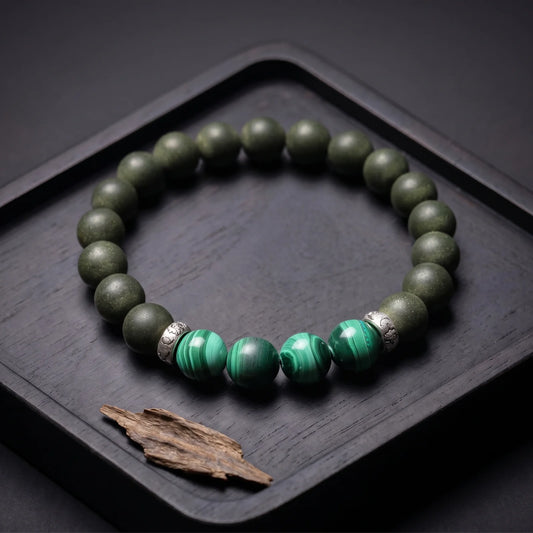 EAST PAVILION wearable incense bracelet placed on a dark tray with agarwood material.