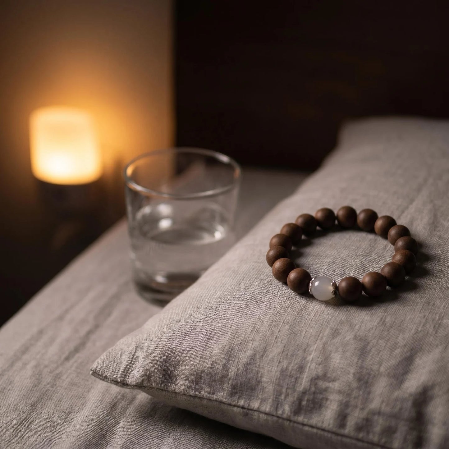 STILL MOON wearable incense bracelet placed beside a warm bedside lamp for an evening wind-down ritual.