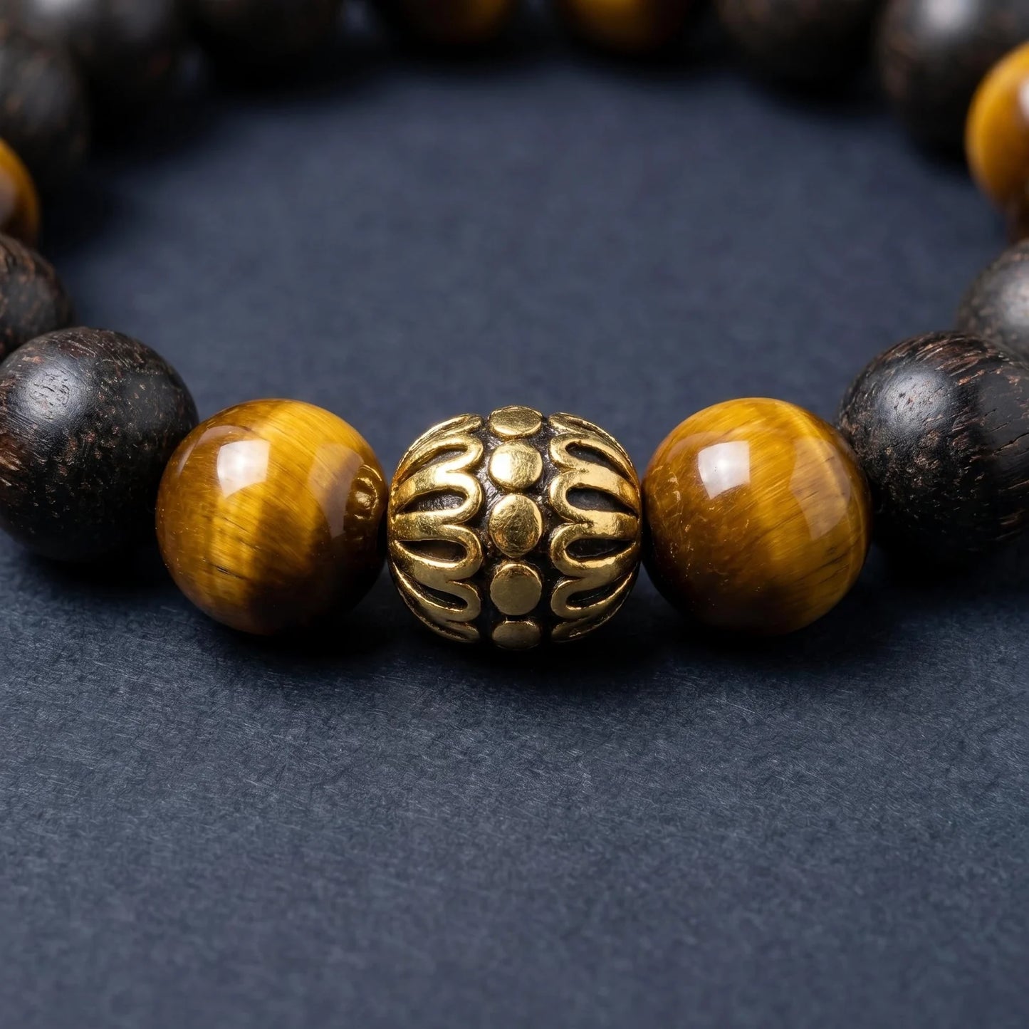 BLACK ACCORD bracelet close-up showing tiger eye beads and a gold-toned lotus detail.