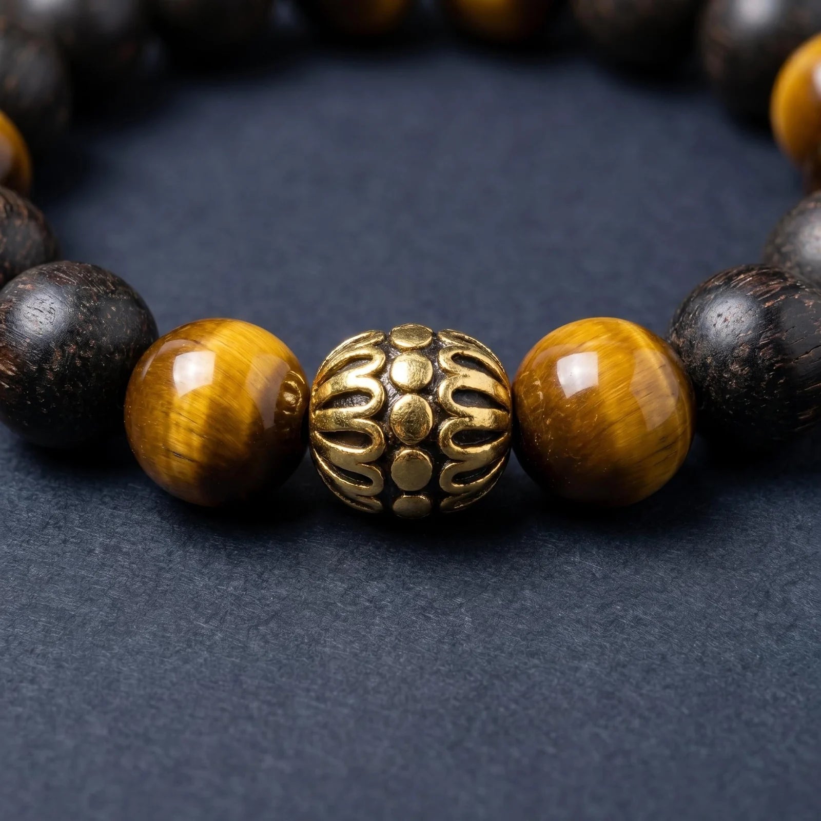 BLACK ACCORD bracelet close-up showing tiger eye beads and a gold-toned lotus detail.