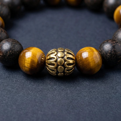 BLACK ACCORD bracelet close-up showing tiger eye beads and a gold-toned lotus detail.