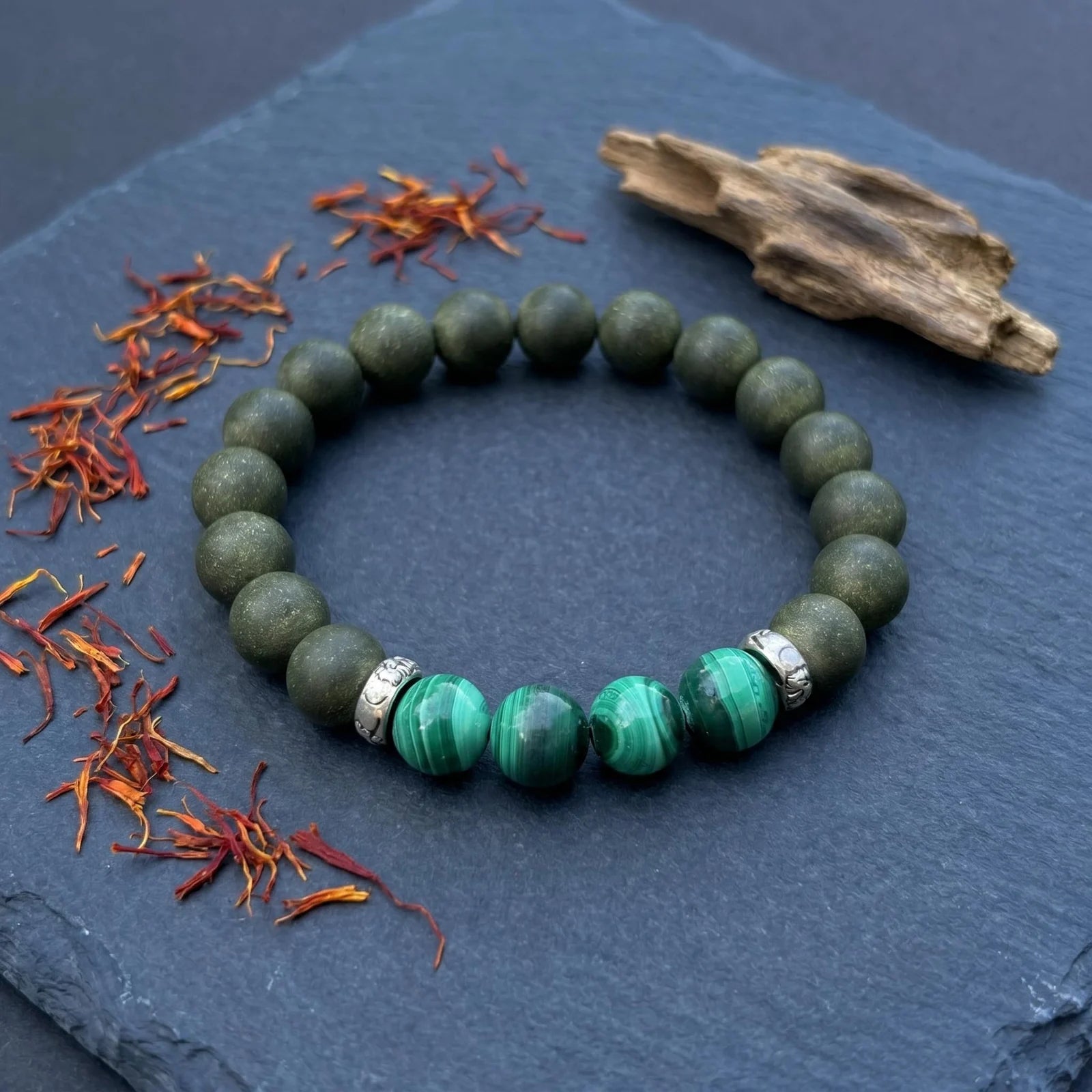 EAST PAVILION bracelet flat lay with saffron, agarwood, and green bead details for a botanical formula story.