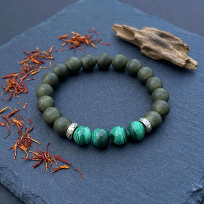 EAST PAVILION bracelet flat lay with saffron, agarwood, and green bead details for a botanical formula story.