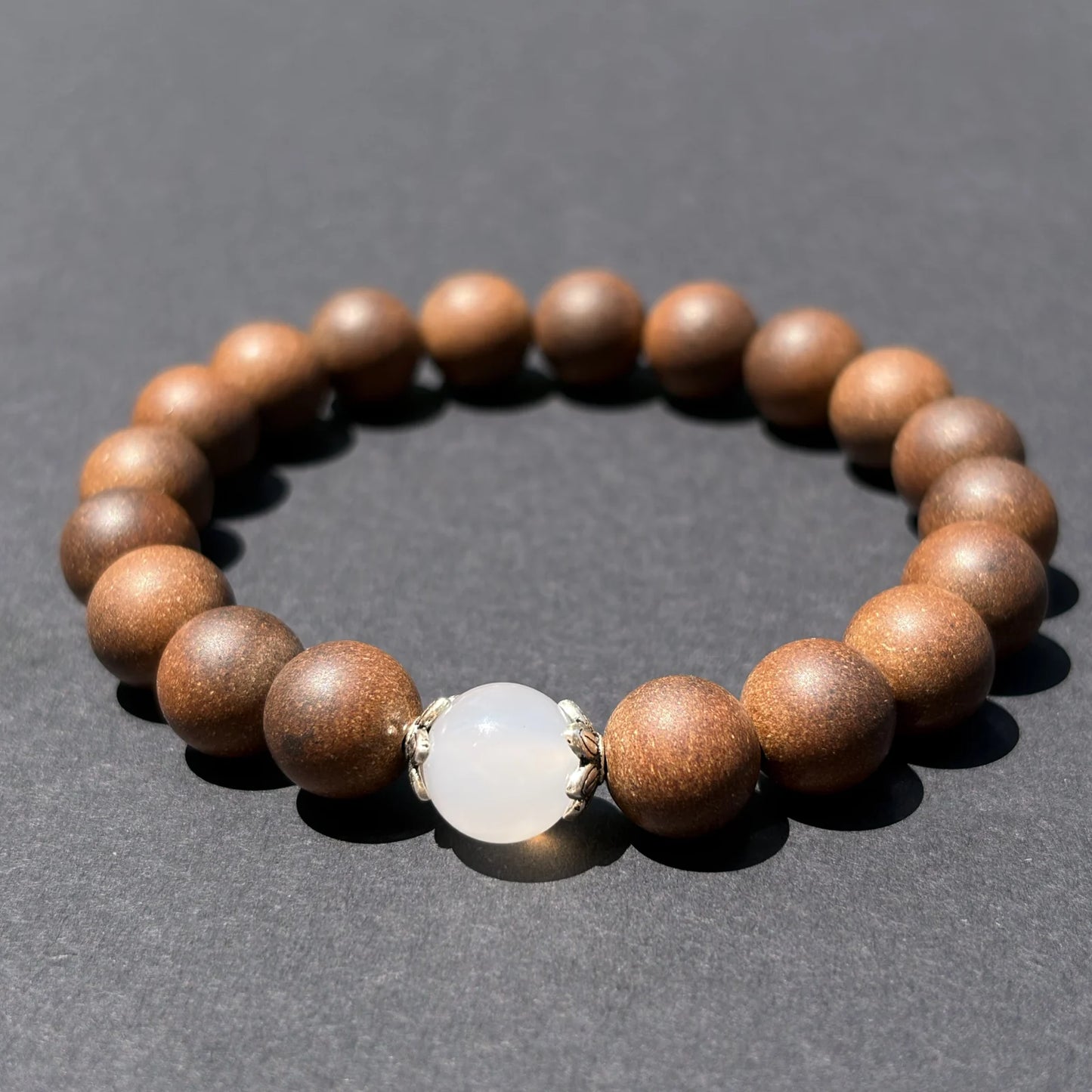 STILL MOON aromatic bead bracelet shown from an angled view on a clean gray surface.