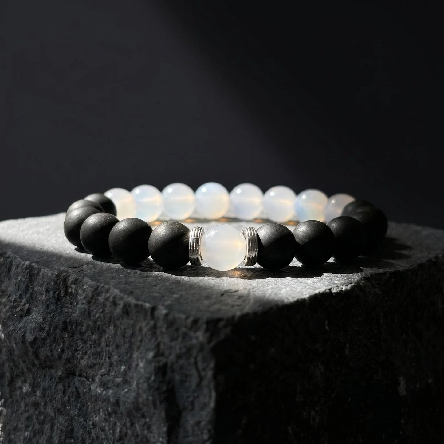 SKIN BREATH black and white wearable incense bracelet placed on dark stone with soft shadow.