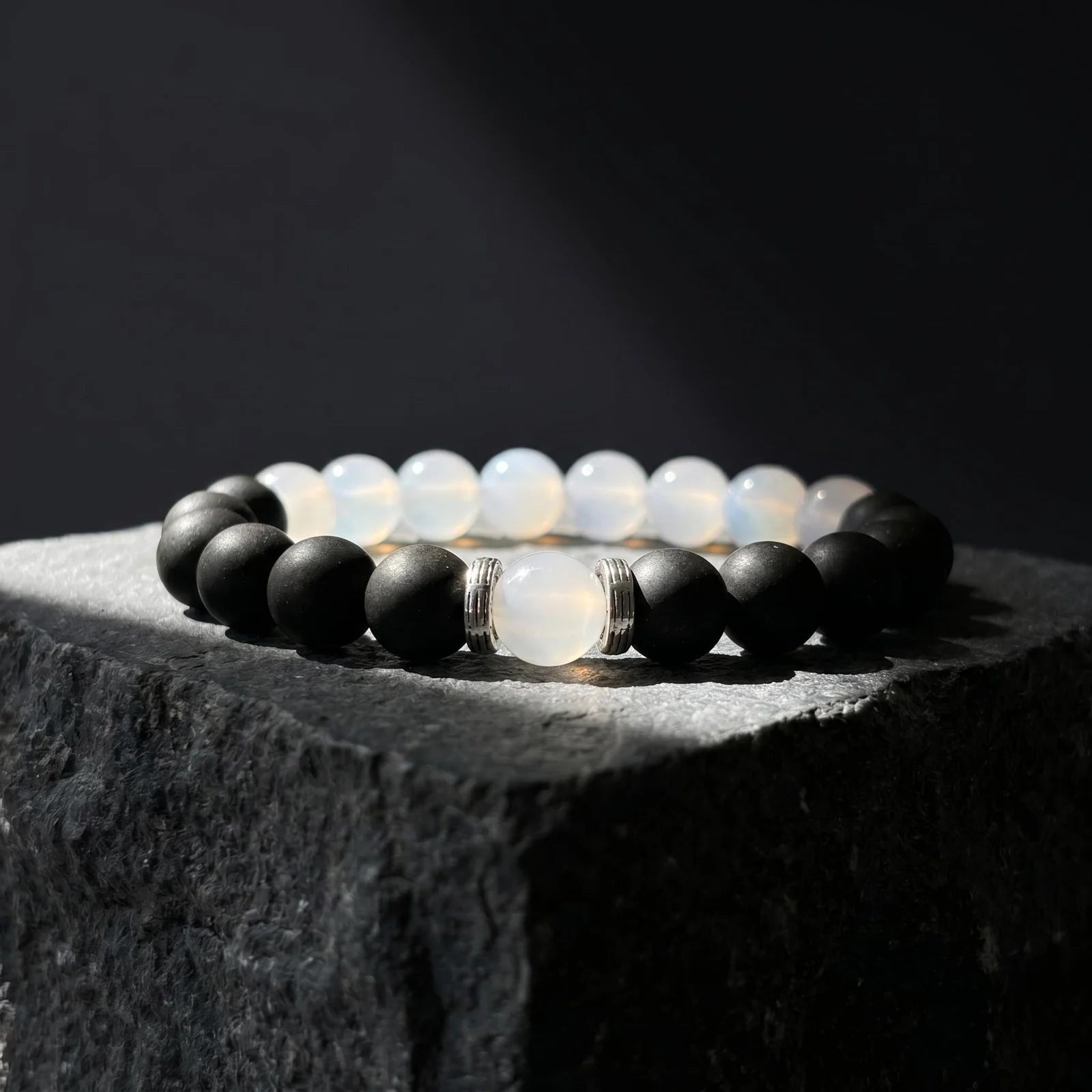 SKIN BREATH black and white wearable incense bracelet placed on dark stone with soft shadow.