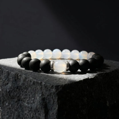 SKIN BREATH black and white wearable incense bracelet placed on dark stone with soft shadow.