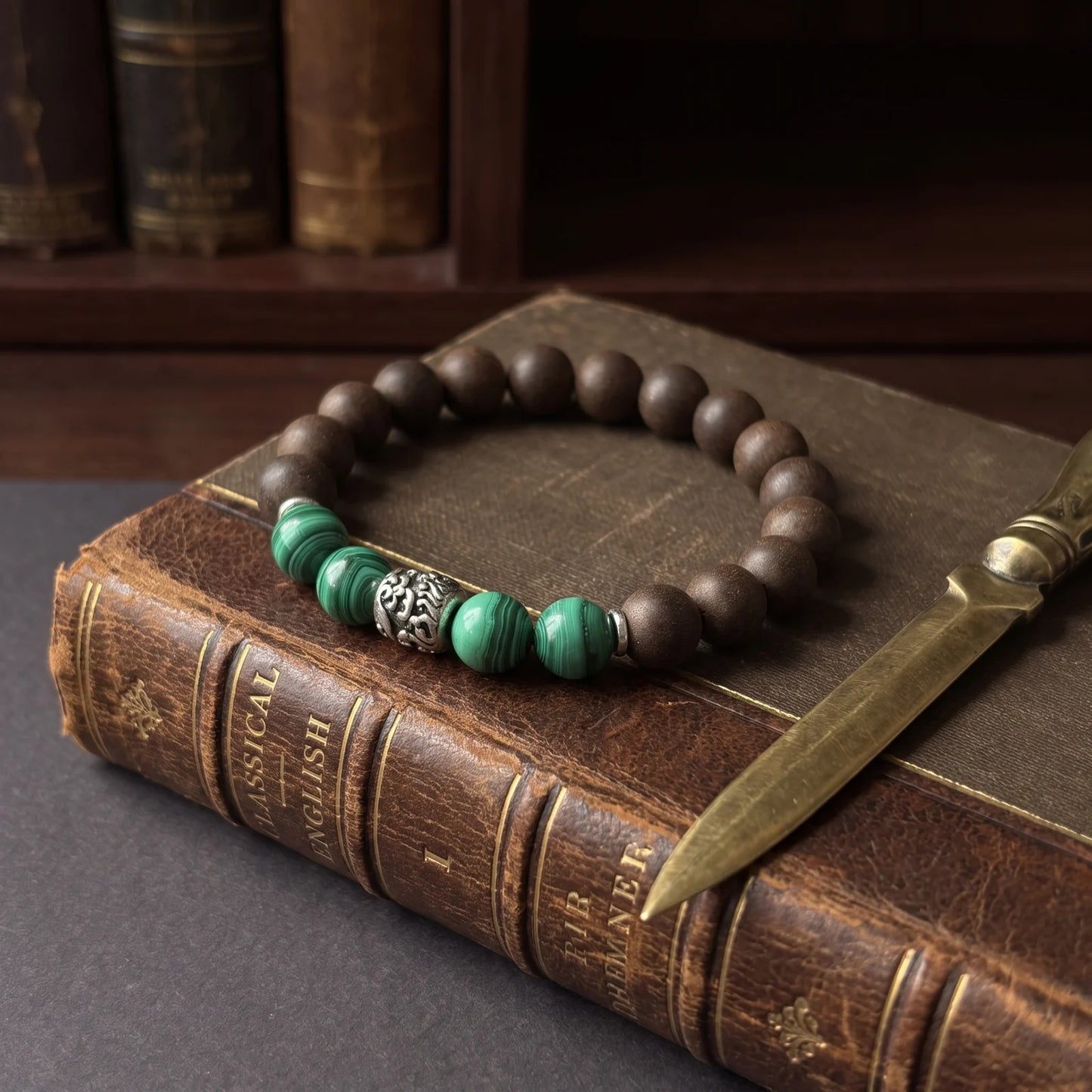 YONGZHENG COOL wearable incense bracelet placed on aged books with a pen for an editorial archive scene.
