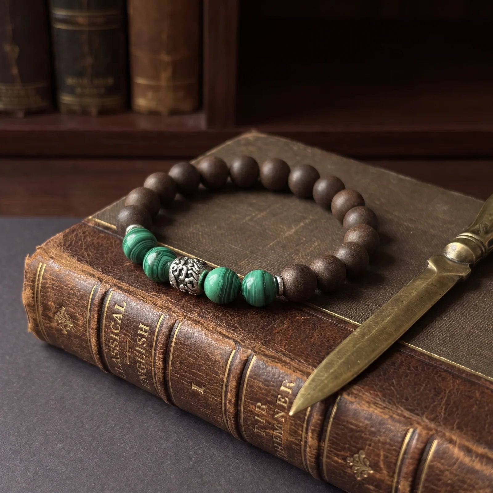 YONGZHENG COOL wearable incense bracelet placed on aged books with a pen for an editorial archive scene.