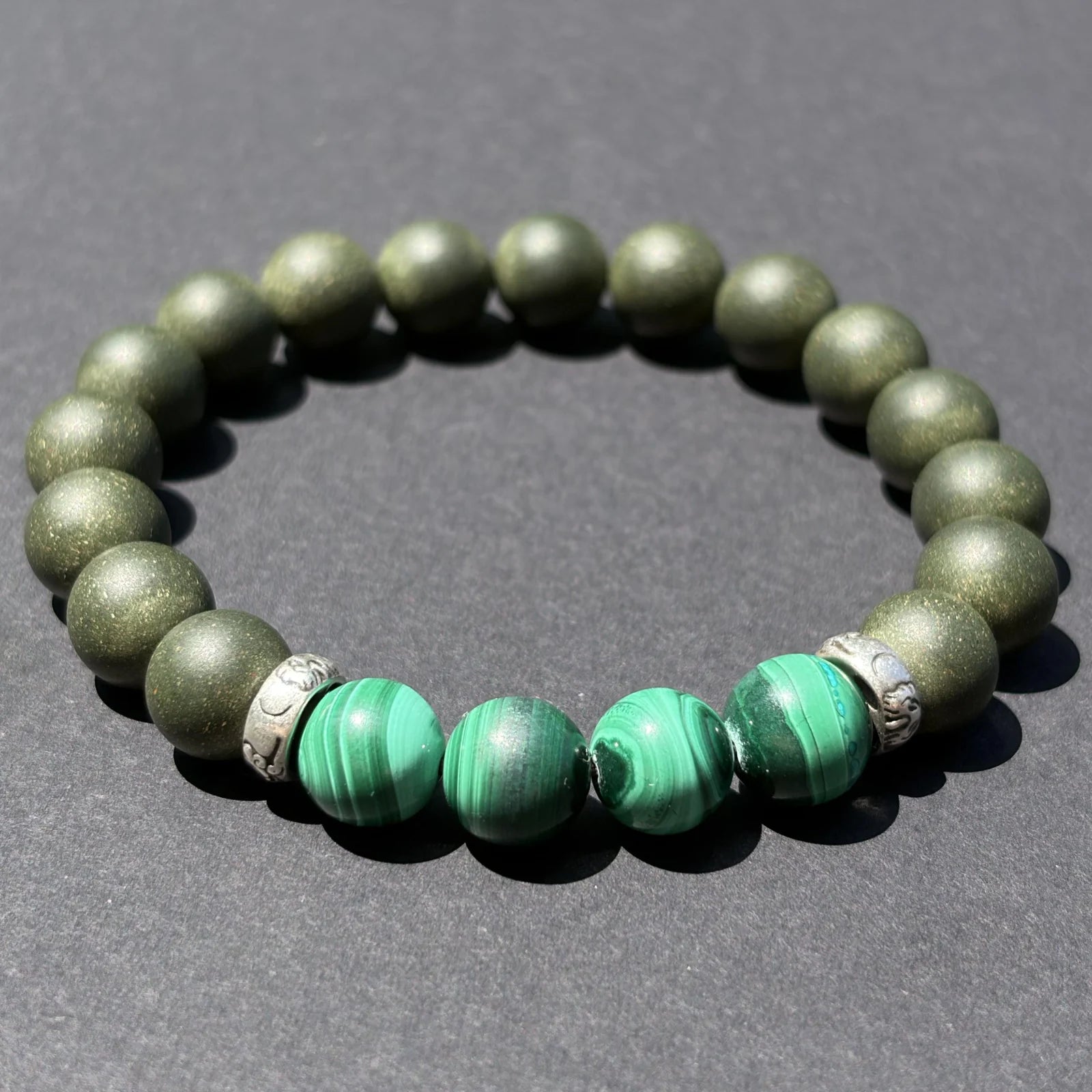 EAST PAVILION green aromatic bead bracelet shown from an angled view on a dark surface.