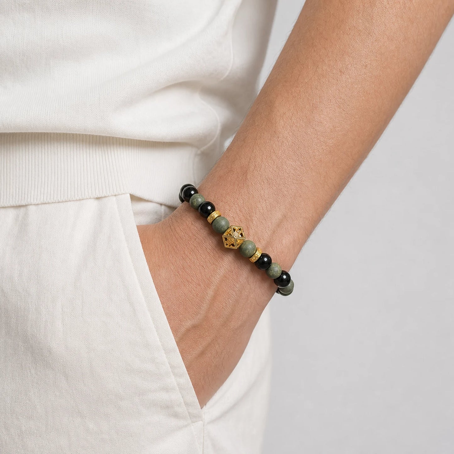 CENSEROOT Azure Dragon wearable solid incense bracelet worn with a cream knit top and trousers, showing blue-green aromatic beads, dark accents, and a Guge-inspired gold spacer.