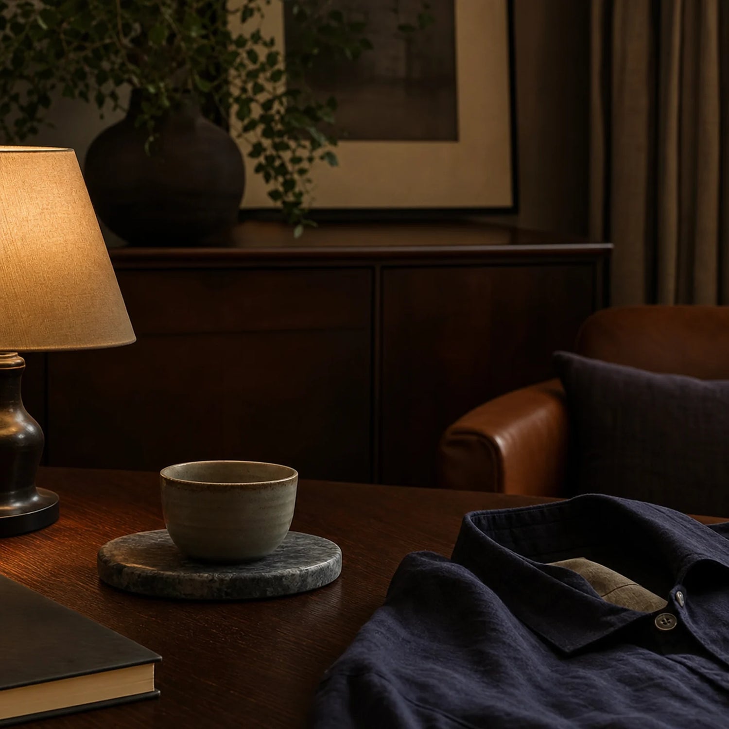 CENSEROOT Gilded Regent scene image showing a restrained evening lounge with walnut wood, warm lamplight, stone, ceramic, and a dark overshirt.